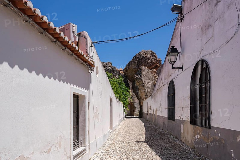 Narrow alley between white walls and cobblestones in sunshine, Serpa, Beja, Portugal