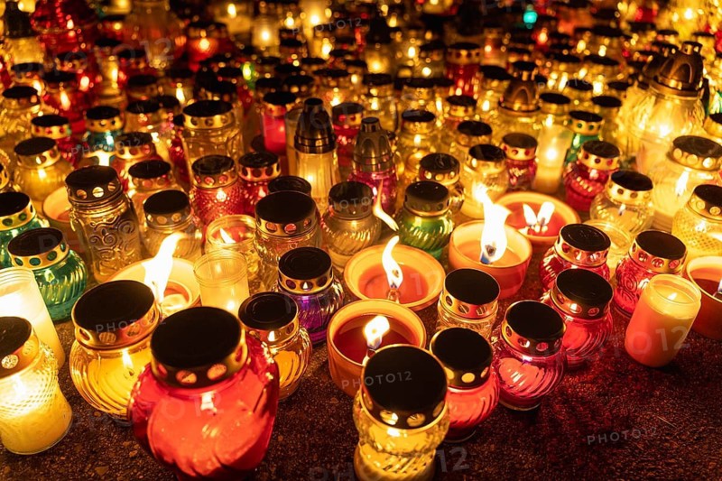 Colorful candlelight jars illuminating the night. A huge number of multicolored burning candles and lamps at a cemetery during All Saints' Day celebrations. Warsaw, Poland