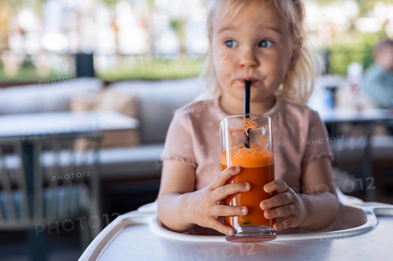 Close-up of glass of fresh carrot juice in child hands