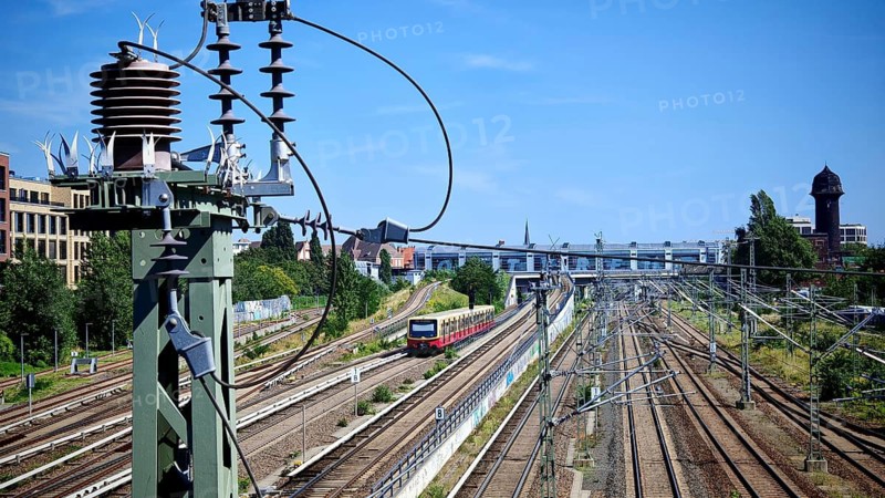View from Modersohn Bridge over landscape with train tracks towards Ostkreuz station, power lines and water tower in the urban area, Friedrichshain, Berlin