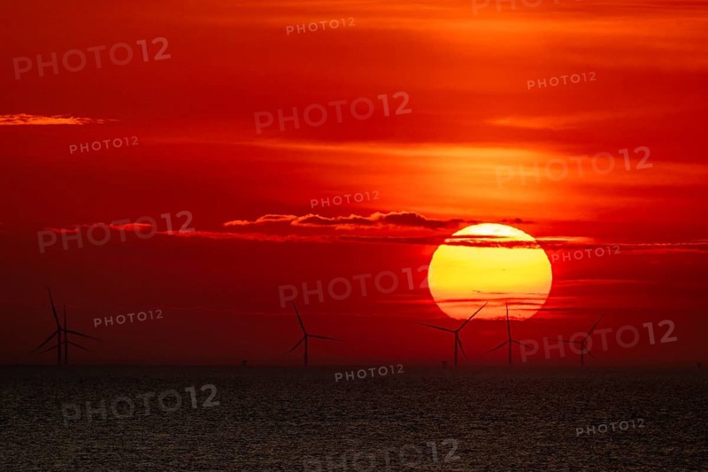 Dramatic sunset over the sea, wind turbines and wind turbines on the horizon, streaks of clouds, Houvig Beach, North Sea, Denmark