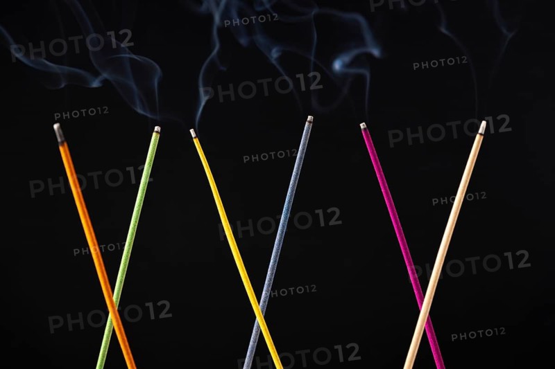 Smoking colorful incense sticks against black background