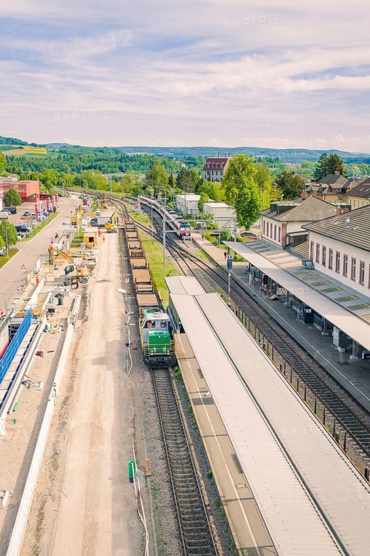 Station in a green landscape with trains and adjacent buildings, construction site by Leonhard Weiss to renovate the station and build the overhead line, Waldshut, Germany