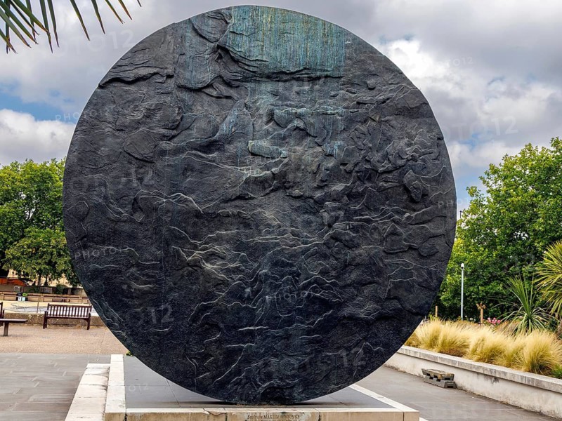 A weathered stone disc with a rippled, wind carved surface stands on its own plinth in the gardens of St Thomas Hospital, forming the sculptural backdrop to the statue of Mary Seacole. Sculptor Martin Jennings designed it to evoke the Crimean landscape, London, England, United Kingdom