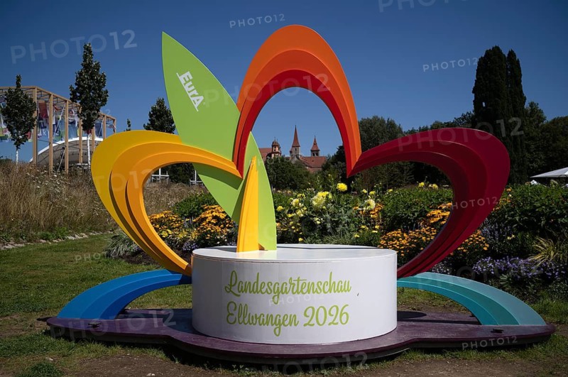 EurA AG logo on a symbol, a sculpture of a flower, with the Protestant Town Church and the monastery's collegiate church – now St Vitus' Basilica – in the background, State Garden Show 2026, Ellwangen (Jagst), Baden-Württemberg, Germany
