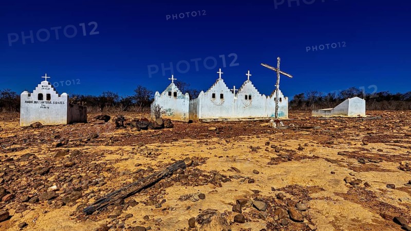 White chapels with crosses in a barren, dry desert landscape under blue skies, cemetery in the thornshrub savanna of Caatinga in the federal states of Pernambuco and Bahia in Brazil