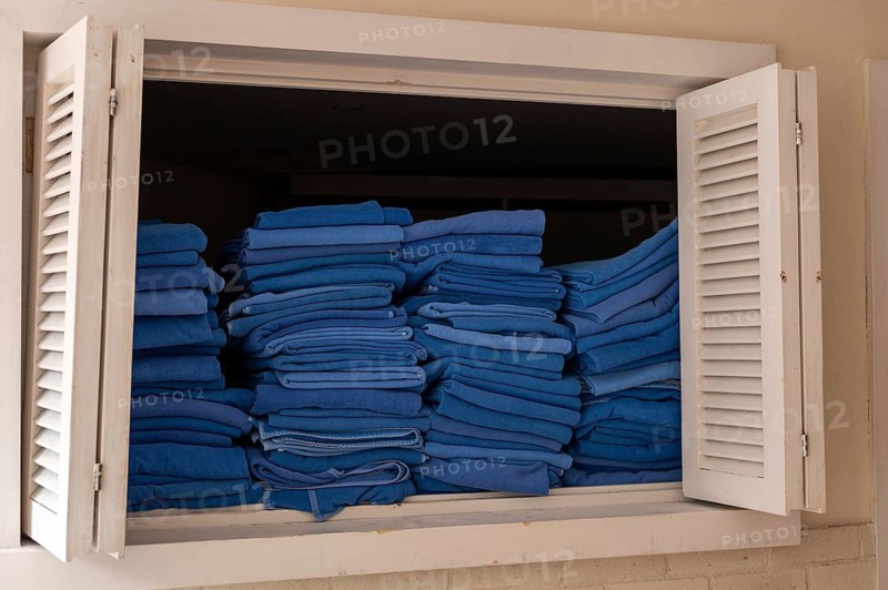 A window displays neatly stacked blue towels in a hotel setting in Turkiye. The towels are folded and piled high, offering a glimpse of the establishments cleanliness and organization
