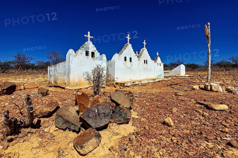 Small chapel with crosses on a dry, rocky area under a bright blue sky, cemetery in the thorny bush savanna of Caatinga in the federal states of Pernambuco and Bahia in Brazil