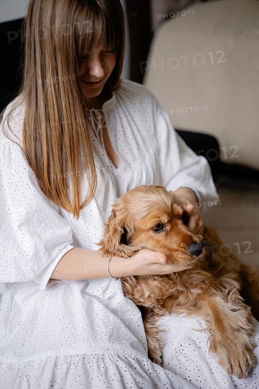 A woman gently cradles a dog in her lap, showing affection and calmness indoors