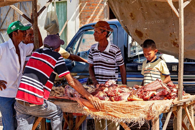 Group of people discussing meat products at a market stand, interacting under tent tarpaulins, market scene in a small town in Caatinga in Bahia and Pernambuco in Brazil