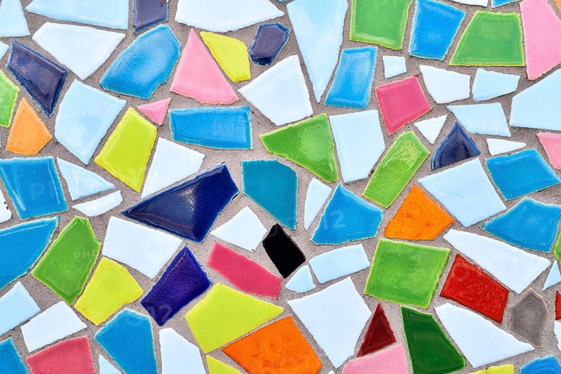 Close up of wall made of irregular colorful mosaic stones, uneven textured decorative surface with vibrant pattern