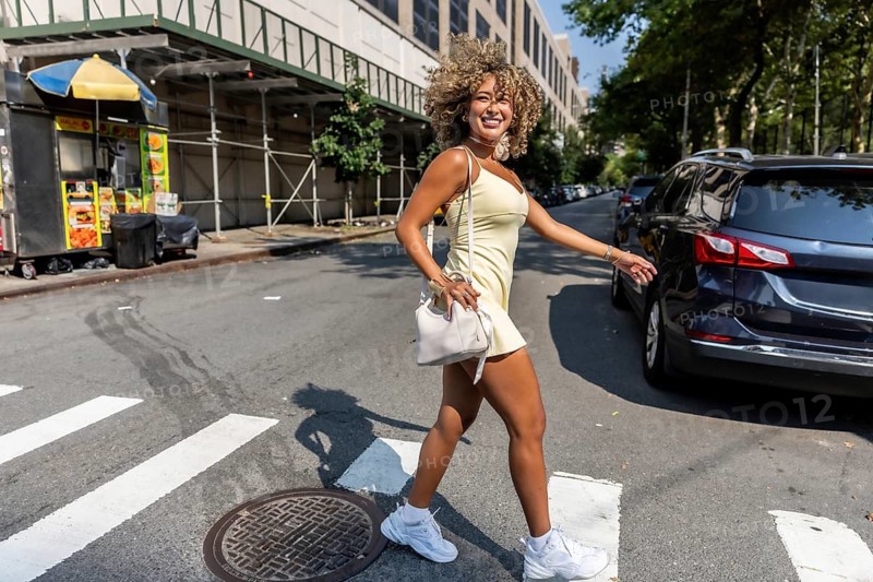 Young happy woman crossing a street on a sunny day in manhattan, embracing the vibrant city lifestyle with joy and freedom during her urban summer walk