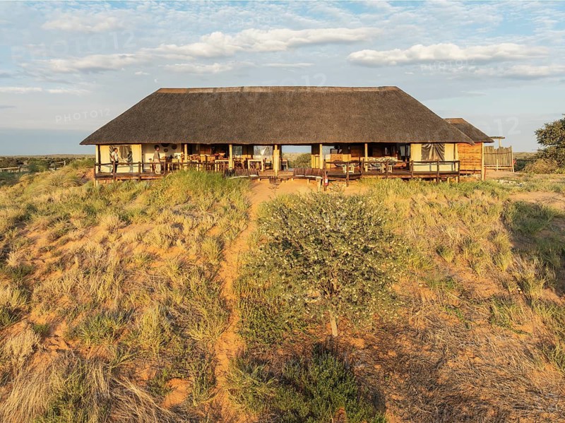 The main building of the Ta Shebube Rooiputs Lodge in the Kalahari Desert during the rainy season with green vegetation. Drone shot. Kgalagadi Transfrontier Park, Botswana