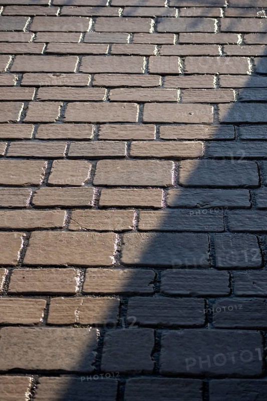 A broad building shadow cuts across rectangular stone paving in strong sunlight, Saint-Tropez, Var, Provence-Alpes-Cote d'Azur, France
