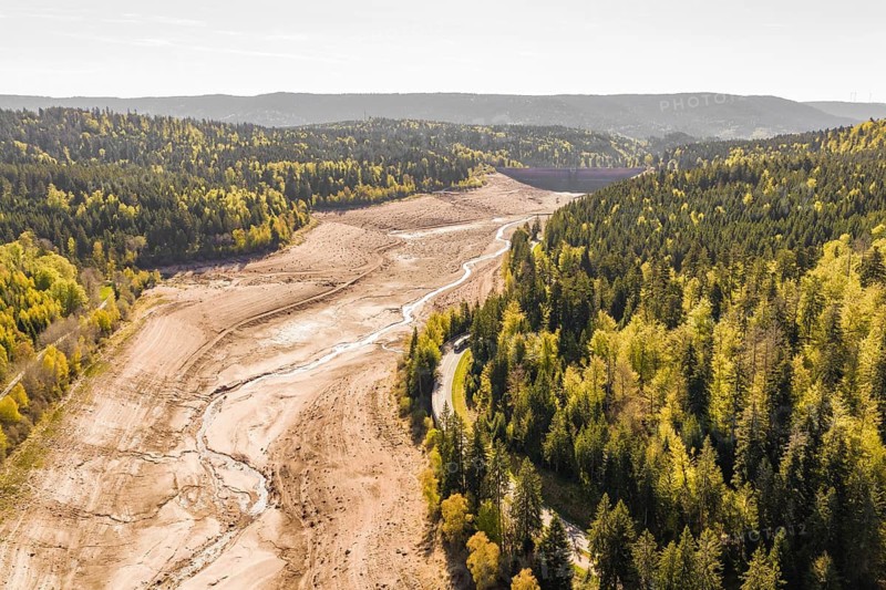Long dry riverbed stretches between forests and hills, emptied Schwarzenbach dam, Forbach, Black Forest, Germany