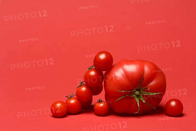 Beef tomato and cherry vine tomatoes with red background