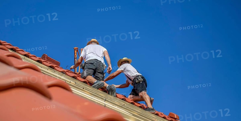 Roofers covering a tiled roof