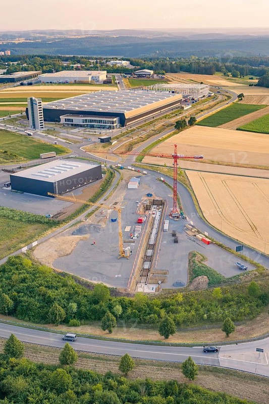 A construction site next to a modern factory in the midst of rural fields, Eisberg, Nagold, Germany