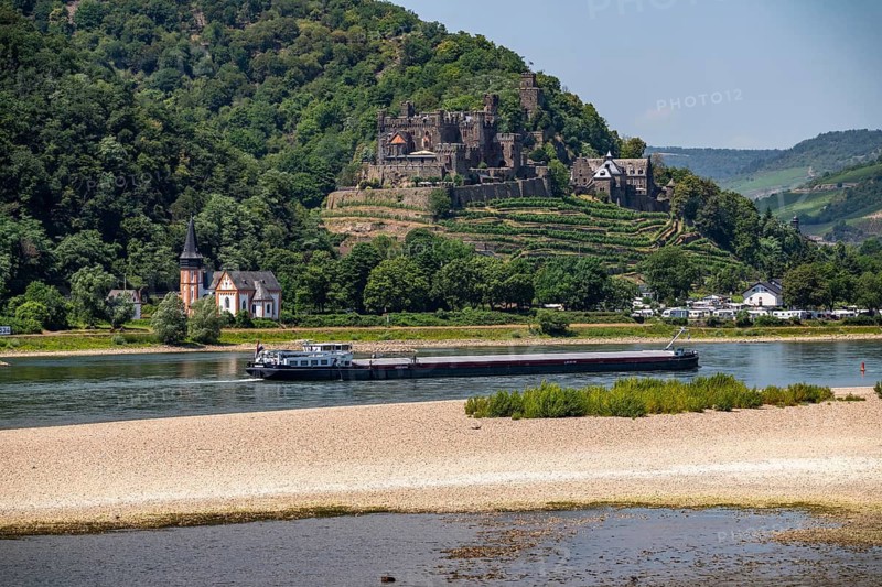 Reichenstein Castle, Burghotel, on the Rhine, St. Clemens Basilica on the left, Clement's Chapel, cargo ship, sandbar at low water, Upper Middle Rhine Valley, Trechtingshausen, Rhineland-Palatinate, Germany