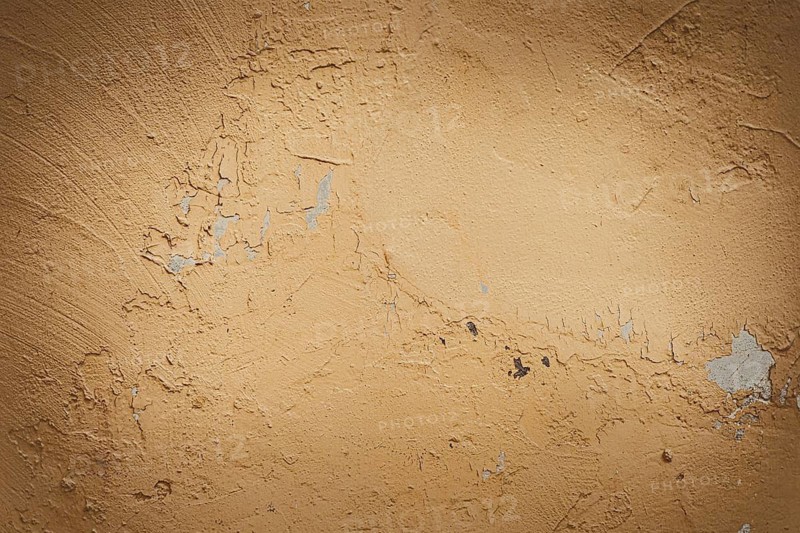 Textured beige wall with subtle imperfections and scratches. The surface appears weathered and rough, showcasing a natural earthy tone