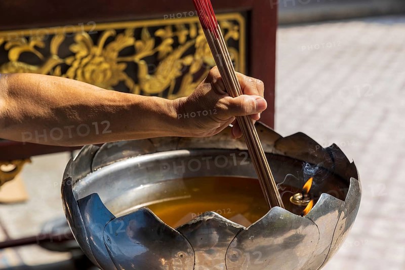 Close view of a devotee offering incense joss sticks at the incense burner of Singapore's oldest Hokkien temple, Thian Hock Keng Temple, Singapore
