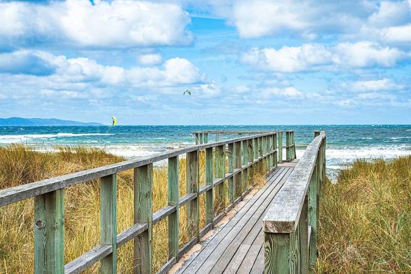 A wooden walkway leads across a dune to the beach in Vejbystrand, Skåne, Sweden. A wooden footbridge leads over a dune to Vejbystrand beach in Scania, Sweden