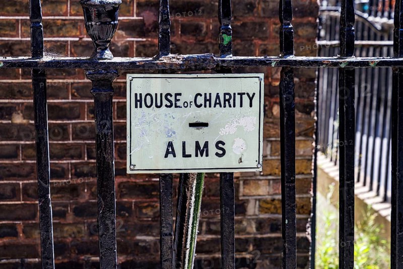 A House of Charity sign marks a victorian penny chute set into the railings that once let passers by donate coins, London, England, United Kingdom