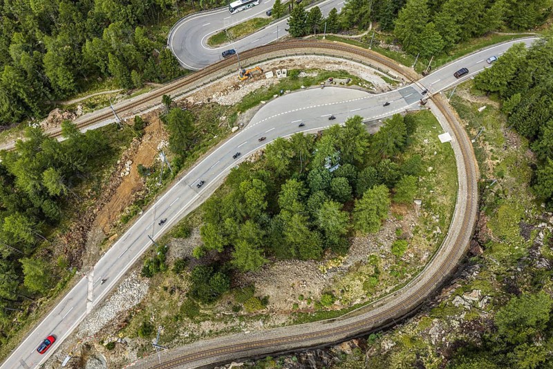 Red train of the Rhaetian railroad line, Bernina Express, 180 degree turn at the Montebello curve, aerial view, Morteratsch, Switzerland