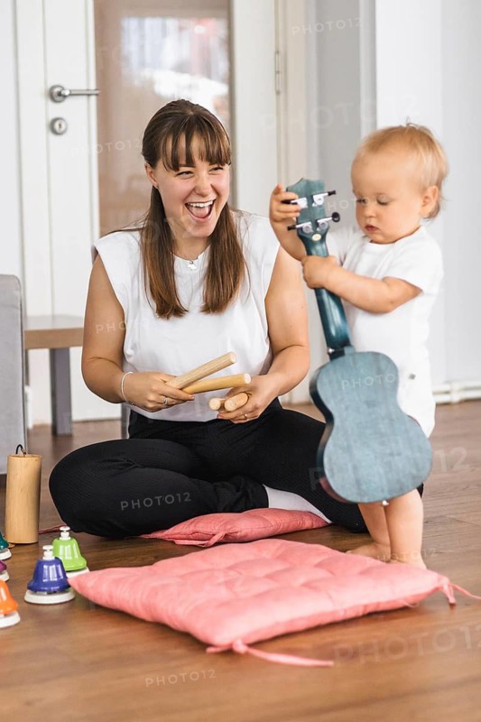 A joyful moment between mother and child playing musical instruments at home