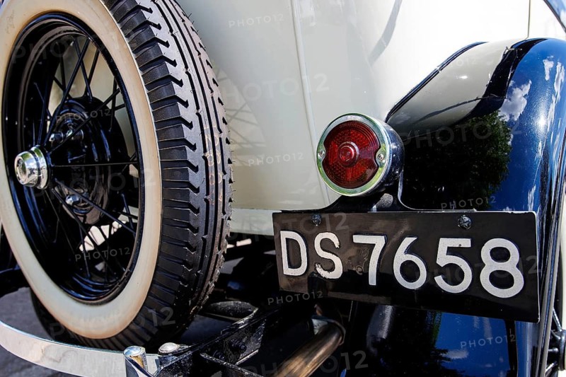 Whitewall wire wheel and black registration plate on a cream vintage tourer