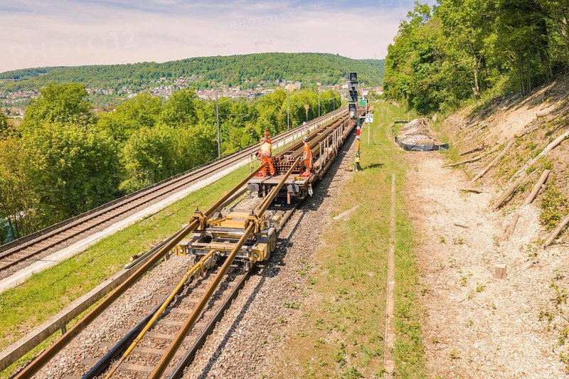 Railway workers working on tracks surrounded by green landscape and blue sky, construction site by Leonhard Weiß to renovate the station and build the overhead line, Waldshut, Germany