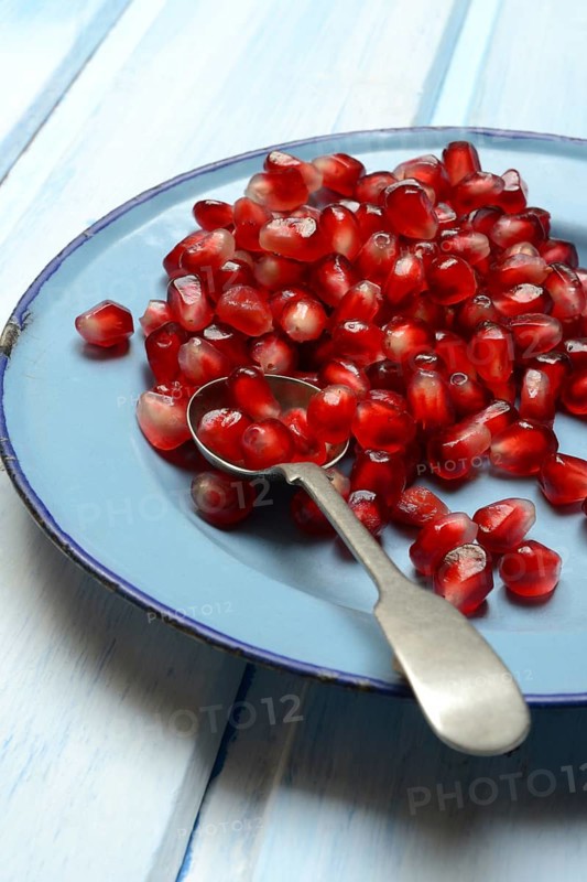 Pomegranate seeds and spoons on plate, Punica granatum