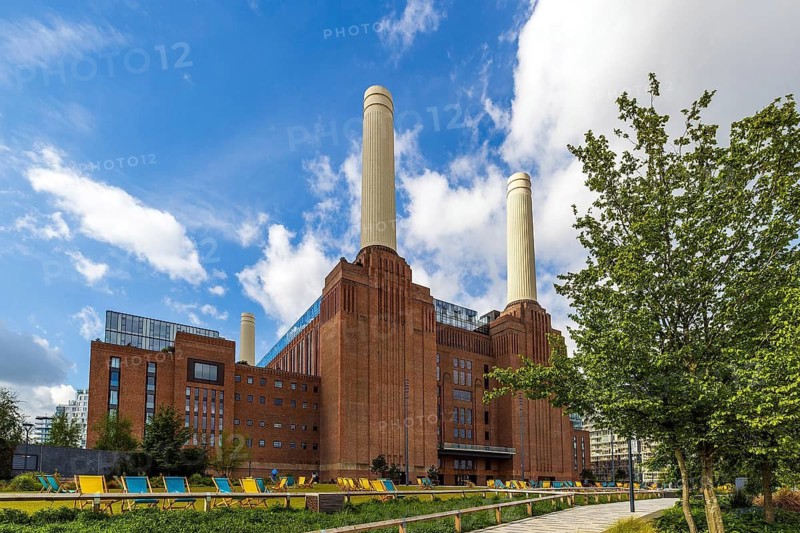 Fresh spring leaves frame the twin Art Deco chimneys of Battersea Power Station, London, England, United Kingdom