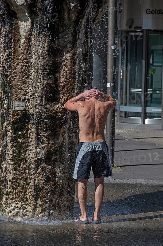 Young man refreshes at a well in the summer heat, Nuremberg, Middle Franconia, Bavaria, Germany