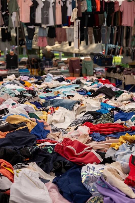 Mixed clothing items heaped in a vibrant outdoor market setting