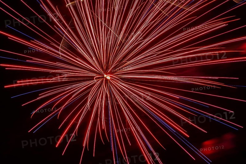 Red and blue illuminated trailing streaks of fireworks with zoom effect in black sky at night in summer, Quebec, Canada