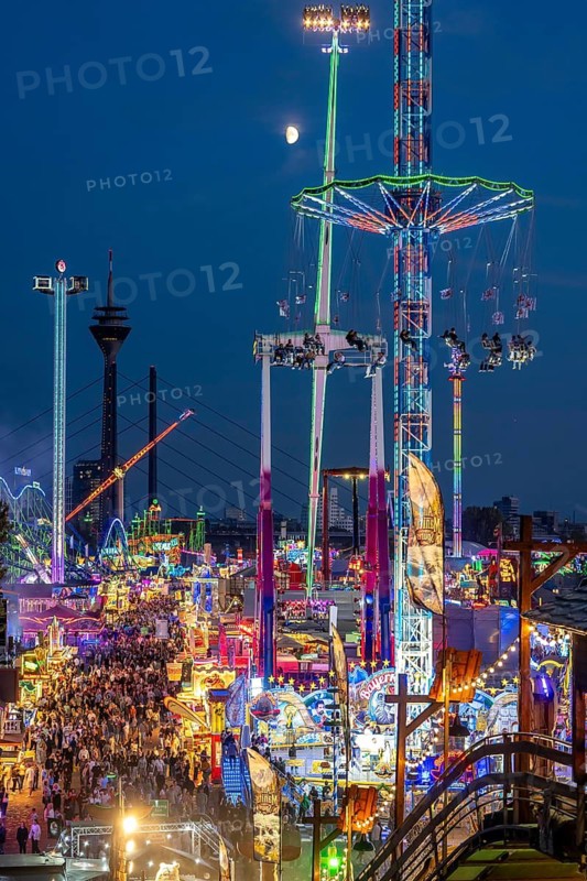 Rhine fair in the Rheinwiesen in Düsseldorf-Oberkassel, view towards the Rhine Tower, Rheinkniebrücke, rides, fairground stands, full corridors, lots of visitors, North Rhine-Westphalia, Germany