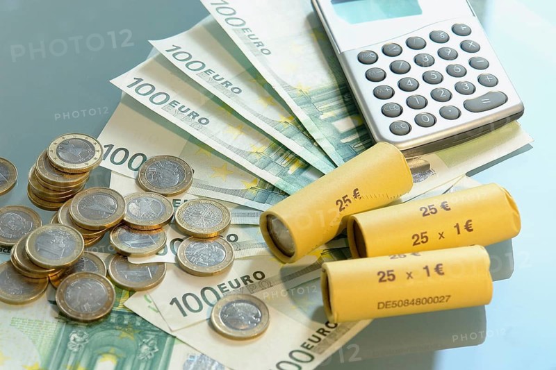 A pocket calculator and euro coins on the table, studio photo, Lower Saxony, Federal Republic of Germany