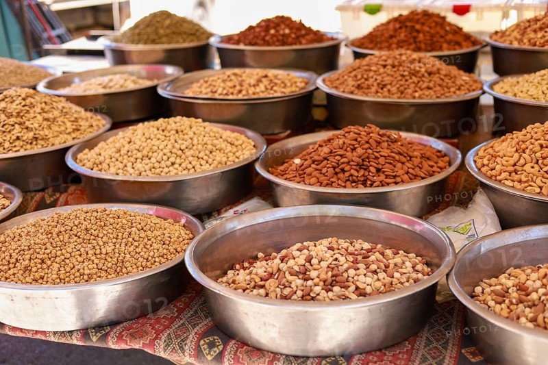 Various nuts and seeds presented in metal bowls at a market stall