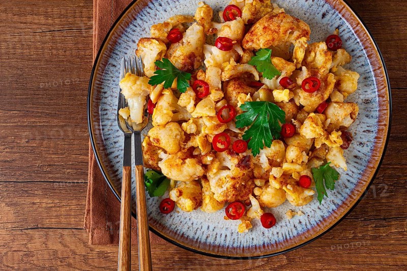 Spicy fried cauliflower served on a wooden countertop