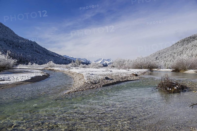 Isar valley in winter at temperatures of minus 18 degrees Celsius. Snow covered landscape with the Isar river flowing through. Some hoar frosted trees. Early morning