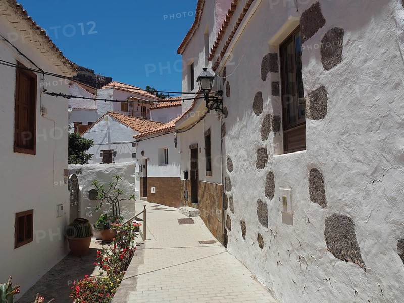 Narrow alley with white buildings and historic style flowers in Fataga, Barranco de Fataga, Gran Canaria, Spain