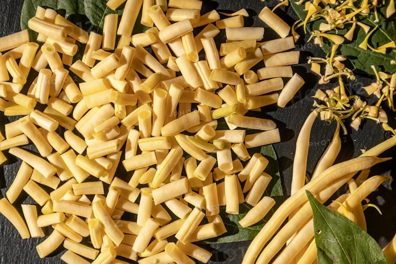 Fresh yellow beans with sliced pieces on a dark background