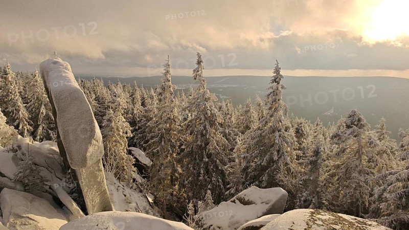 Snowy landscape with rocks, sunlight illuminates the trees and the horizon, Fichtelgebirge nature park Park, Upper Franconia