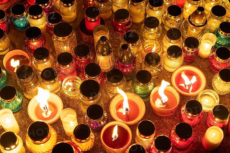 Colorful candle jars glowing warmly in the night. A huge number of multicolored burning candles and lamps at a cemetery during All Saints' Day celebrations. Warsaw, Poland