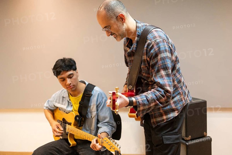 Two musicians collaborate in a recording studio, focusing on guitar techniques. The scene captures creativity and musical synergy in a professional setting