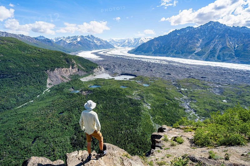 Young man enjoying the view, view of impressive mountain landscape with Matanuska glacier and glaciated mountain peaks, Lion's Head, Chugach Mountains, Alaska, USA