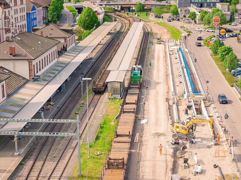 Trains and construction work next to a platform, surrounded by roads, construction site by Leonhard Weiß to renovate the station and build the overhead line, Waldshut, Germany