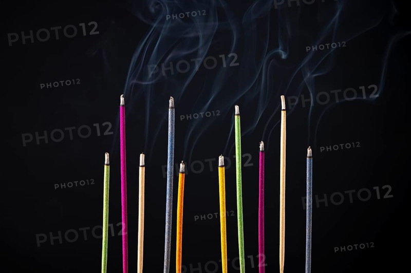 Colourful smoking incense sticks on black background