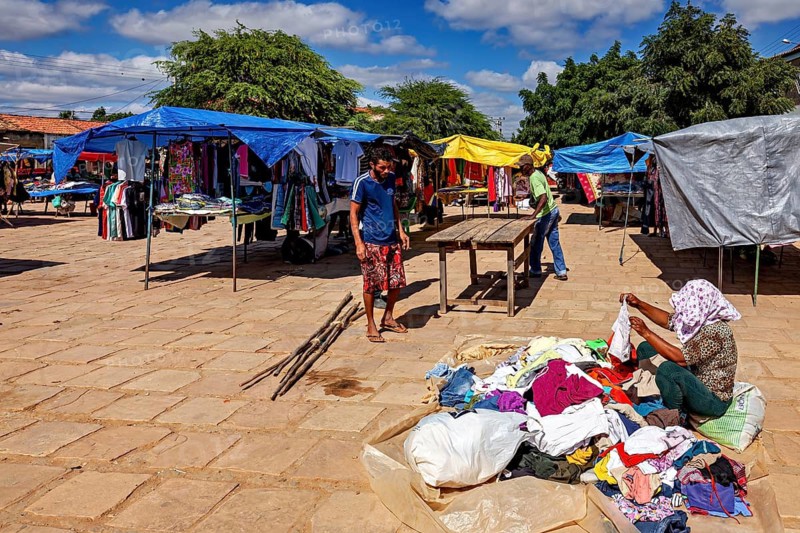 Colourful clothes spread out at a market with people inspecting goods under blue skies, market scene in a small town in Caatinga in Bahia and Pernambuco in Brazil